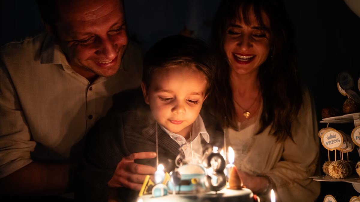 A joyful family moment with a child blowing out birthday candles on a cake.